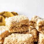 Pinterest image of a pile of Caramel Rice Krispie Treats on a wooden serving platter.
