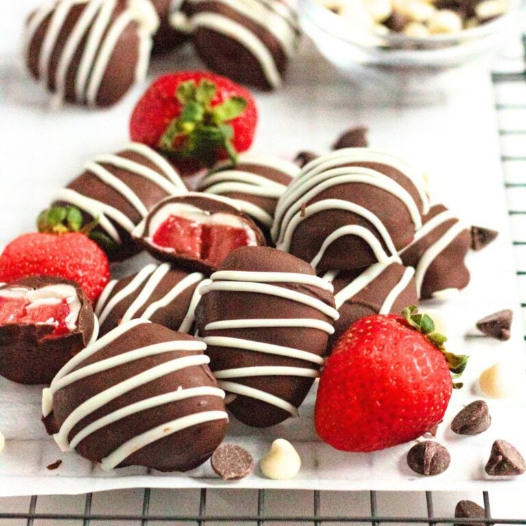 A pile of Frozen Chocolate Covered Strawberries next to chocolate chips on a piece of parchment paper.