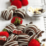 Pinterest image of a stack of chocolate-dipped frozen strawberries lying amongst whole strawberries on a parchment paper-covered cooling rack.