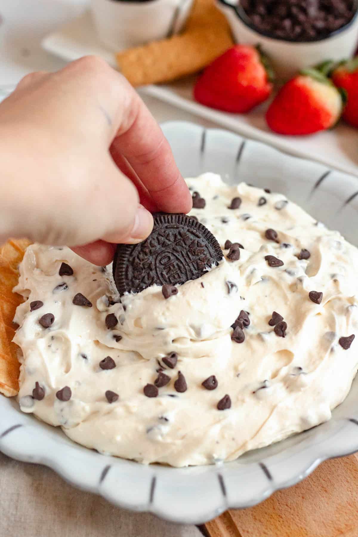 Hand dipping an oreo into booty dip.