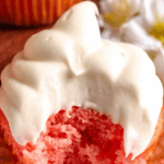 Pinterest image of a close-up shot of a strawberry cupcake piped with Cool Whip Cream Cheese Frosting, with a bite taken out of it.