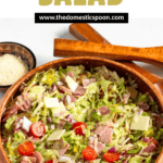 Pinterest image of wooden serving tongs resting next to a big bowl of grinder salad recipe tossed in a delicious red wine vinegar dressing.