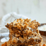 Pinterest image of a close-up shot of 3 Hello Dolly bars on a plate with chocolate and butterscotch chips lying around them.