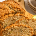 Pinterest image of slices of freshly baked zucchini bread on a cutting board with thin slices of fresh zucchini alongside it.