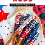 Pinterest image of colorful Fourth of July pretzel rods resting on a platter with red, white, and blue stars on the tablecloth and colorful candy melts beside it.