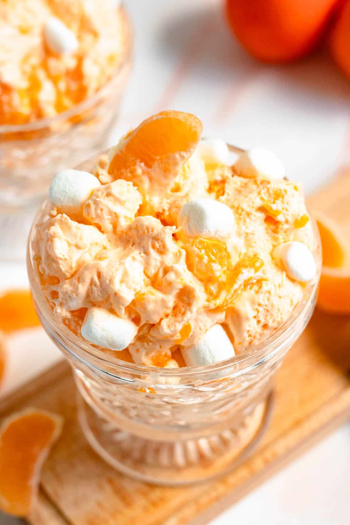 Top view of a glass filled with orange dreamsicle salad with mini marshmallows garnished on top.