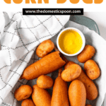 Pinterest image of a top view of a platter filled with air fryer corn dogs and corn dog bites with a small dish of dipping sauce nestled on the side.