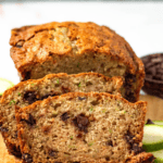 Pinterest image of slices of chocolate chip zucchini bread on a cutting board with chocolate chips and zucchini slices.
