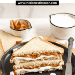 Pinterest image of two halves of a fluffernutter sandwich served on a plate with a butter knife resting on the edge.