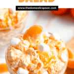 Pinterest image of a glass filled with orange dreamsicle salad with mini marshmallows and an orange slice garnished on top.