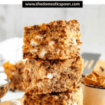 Pinterest image of a stack of 3 chocolate peanut butter Rice Krispies treats with a spoonful of creamy peanut butter laying next to it.