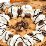 Pinterest image of a close-up shot of Peanut Butter Pretzel Pie in a pie plate topped with whipped cream, drizzled with chocolate sauce, and garnished with mini Reese's peanut butter cups.