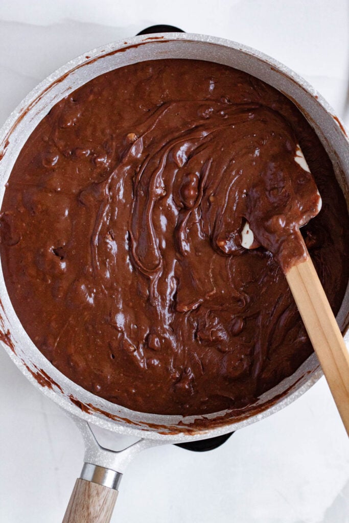 Melted mixture of butter, evaporated milk, sugar, salt, marshmallows, chocolate chips and walnuts in a pot.