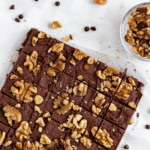Pinterest image of a carnation fudge cut into squares and topped with crunchy walnuts.