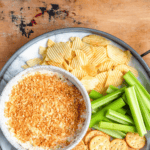 Pinterest image of an overhead shot of the fried pickle dip, chips, celery sticks, crackers, and pickles in a tray, ready to serve.