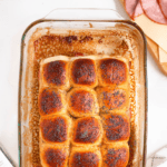 Pinterest image of an overhead shot of the golden-brown baked funeral sandwiches topped with poppy seeds in a glass baking dish.