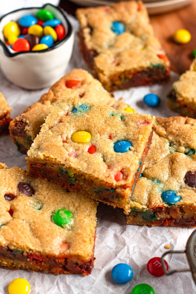 Stacked M&M cookie bars with a small bowl of colorful M&M candies.