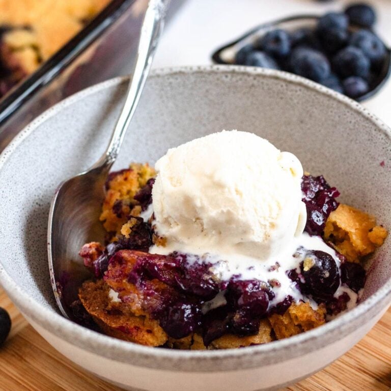 A bowl of warm, gooey 3-ingredient blueberry cobbler topped with ice cream.