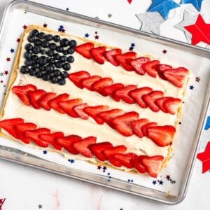 Colorful American flag fruit pizza with blueberries and sliced strawberries on a creamy base.