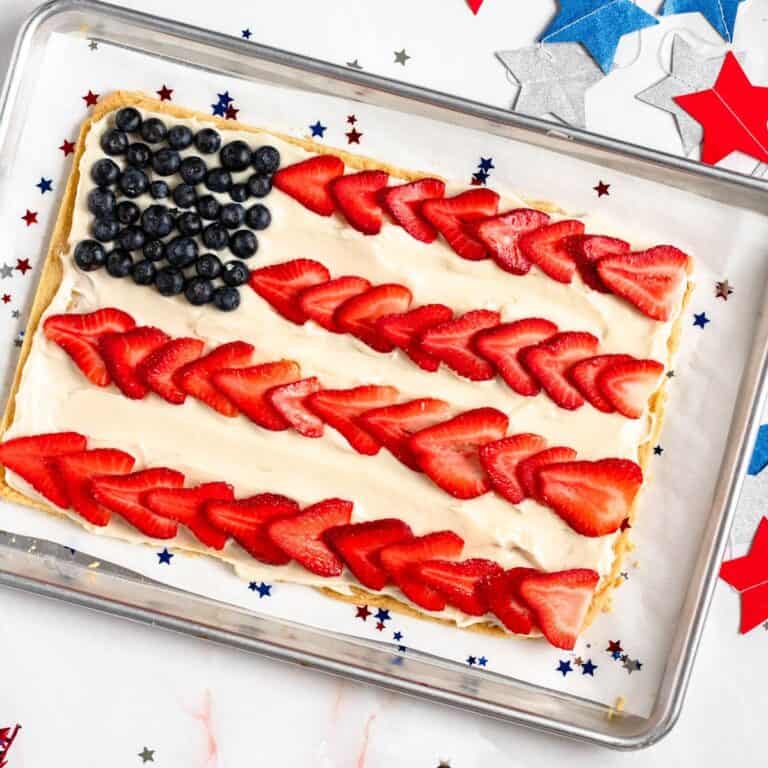 Colorful American flag fruit pizza with blueberries and sliced strawberries on a creamy base.