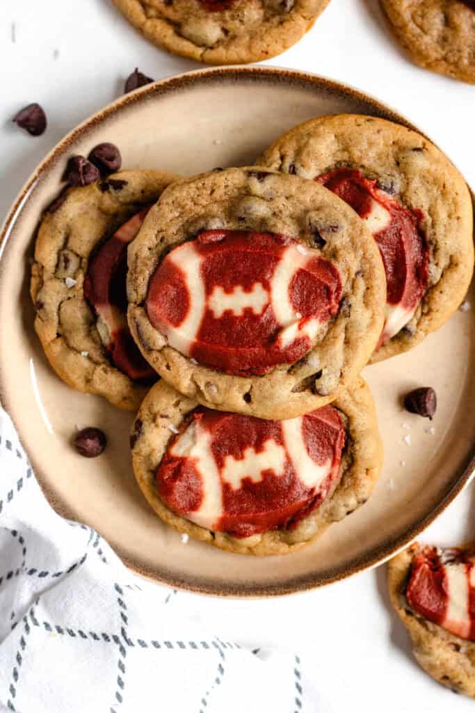 A plate of freshly baked football cookies with chocolate chips on the sides.