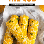 Pinterest image of freshly cooked corn on the cob, topped with butter and salt on a plate.