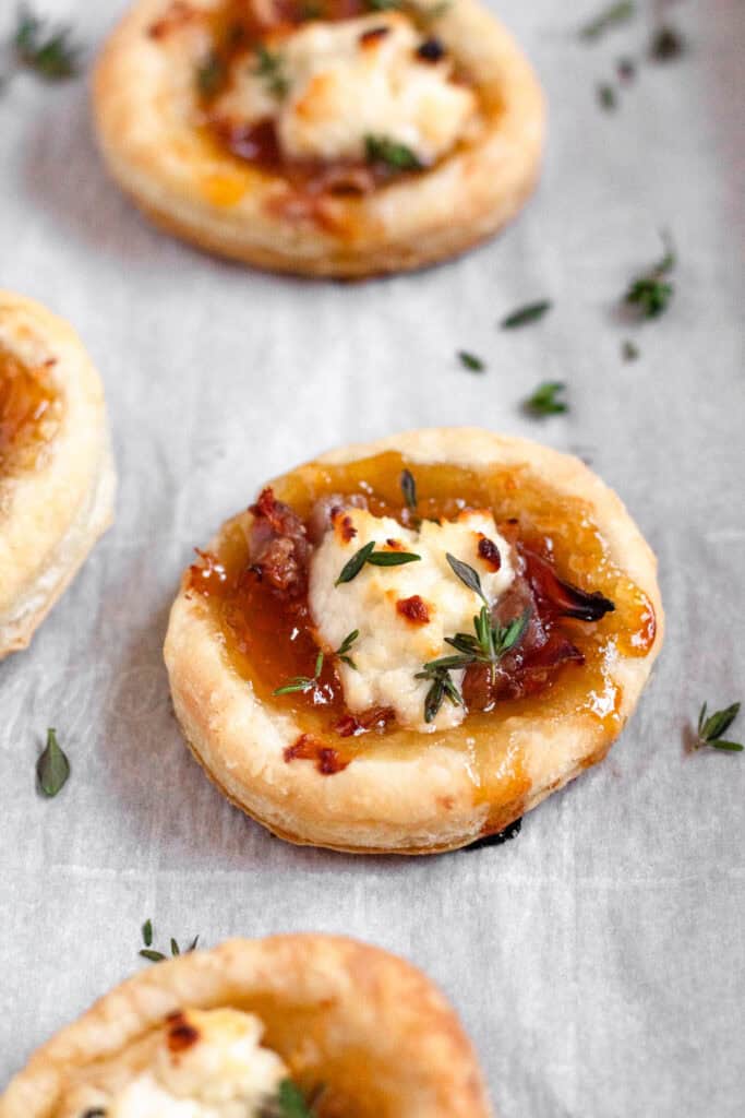 Baked puff pastry appetizers puffed and golden, topped with fresh thyme leaves, ready to serve.