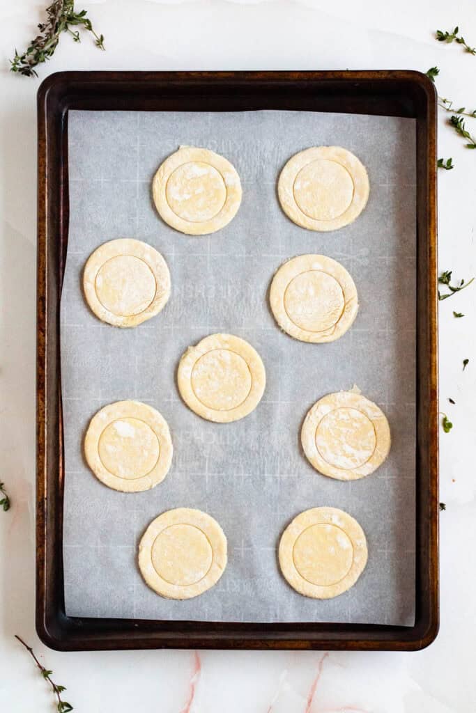 Centers of puff pastry pieces are marked and pressed, leaving the edges untouched.