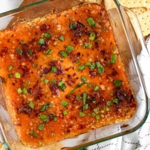 Captain Rodney’s Dip topped with crispy bacon and green onions in a glass dish.
