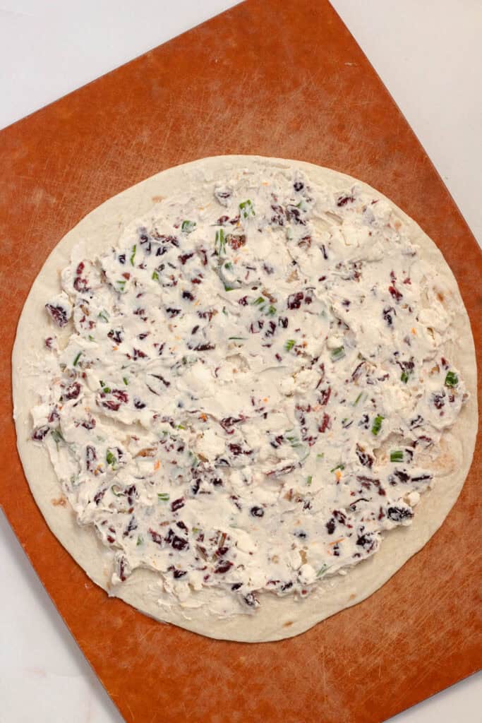 The creamy cranberry filling is spread evenly across a tortilla to the edges.
