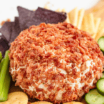 Pinterest image of a close-up shot of the bacon cheese ball served with crackers, cucumber slices, and celery sticks.