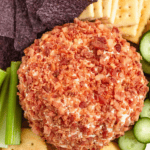Pinterest image of a top-view shot of the bacon cheese ball served with crackers, cucumber slices, and celery sticks.