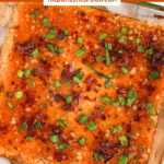 Pinterest image of a top-view shot of Captain Rodney’s Dip topped with crispy bacon and green onions in a glass dish with crackers and parsley on the side.