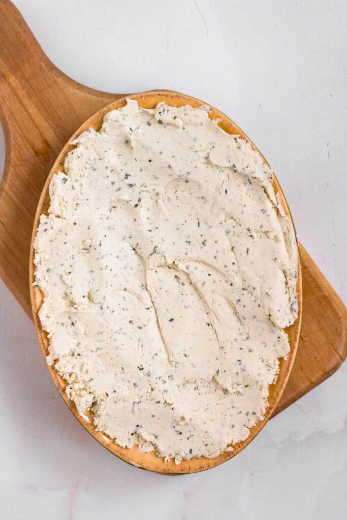 Cold Boursin cheese pressed evenly into the bottom of a serving dish.