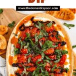 Pinterest image of the top-view of the creamy Bruschetta Dip topped with juicy tomatoes, fresh basil, and balsamic drizzle, served with toasted bread slices.