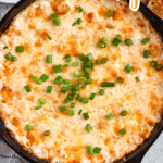 Pinterest image of a top-shot view of the Hot Crab Dip in a Skillet with crostini beside it.