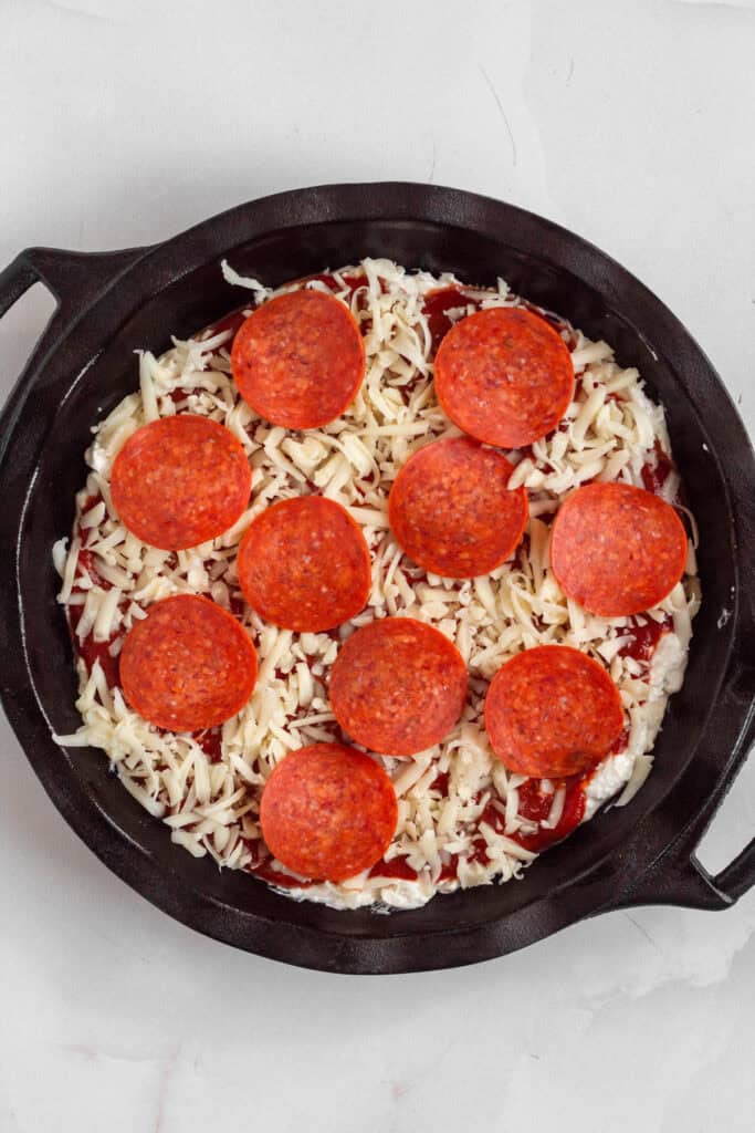 Cheese mixture spread into a baking dish and topped with pizza sauce, shredded mozzarella, and sliced pepperoni.