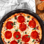 Pinterest image of an overhead shot of freshly baked pizza dip with a golden, bubbly top, fresh out of the oven.