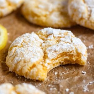 Lemon Cake Mix Cookies dusted with powdered sugar, one with a bite taken out.
