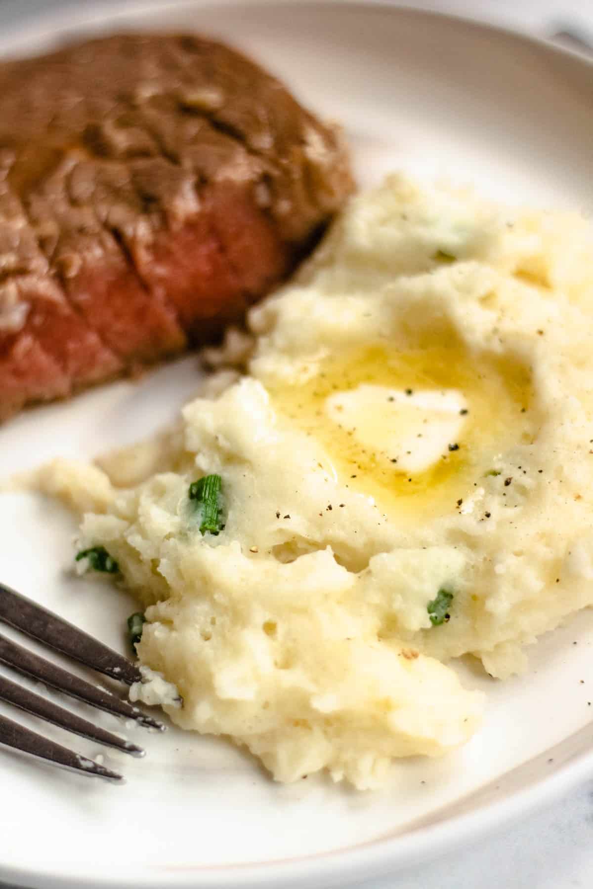 Creamy Horseradish Mashed Potatoes served with steak and melted butter.