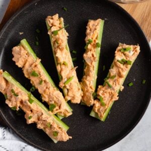 Buffalo Chicken Stuffed Celery on a plate topped with chives.